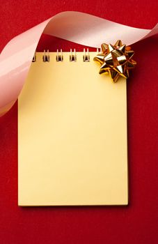 Notepad and bow isolated on red
