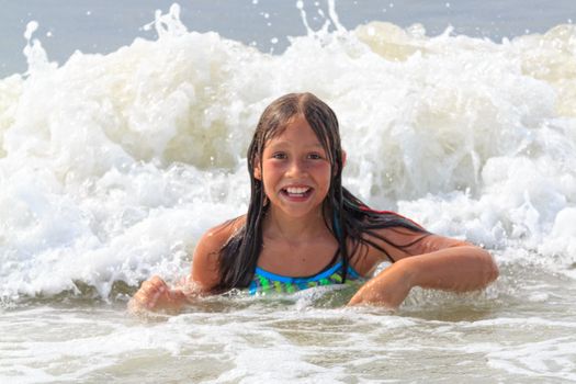 Young girl swimming and playing in the waves in the Atlantic Ocean.