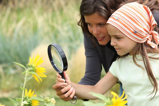 Mother and daughter looking at a flower with a magnifying glass