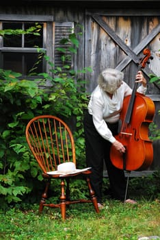 Female cellist standing with her cello outside.