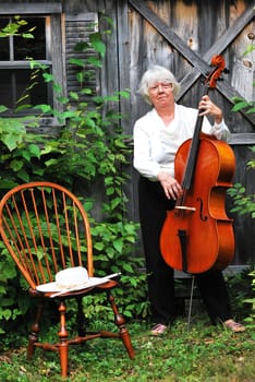 Female cellist standing with her cello outside.