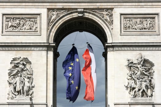 Famous landmark of Paris, France. Arc de Triomphe (Arch of Triumph) located at Place Charles de Gaulle. Flags of EU and France.