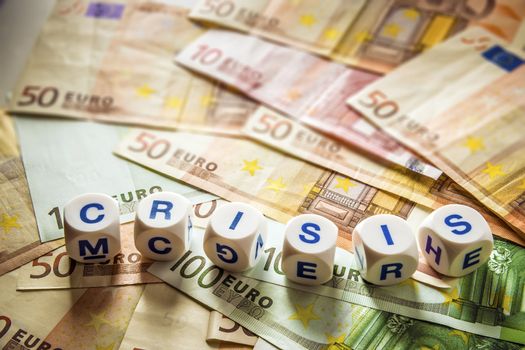 Euro banknotes with white dice with the word crisis