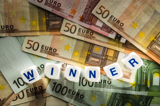 Euro banknotes with white dice with the word Winner