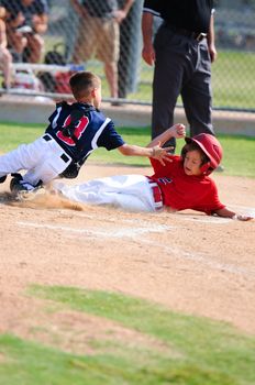 Baseball boy sliding in at home plate during game.