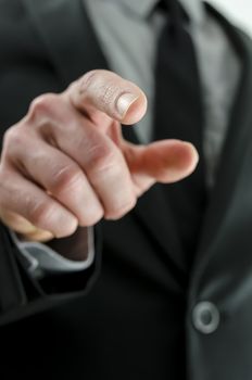 Cropped view of a hand with pointed finger. With businessman in suit in background.