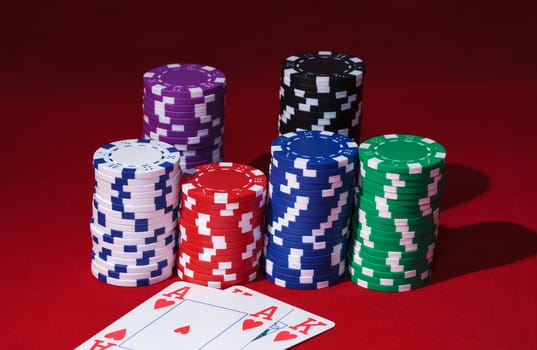 Stacks of Poker Chips with Playing Cards, closeup on red background