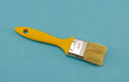 brush 40mm wide with a yellow shaft handle on blue background. paint tool.