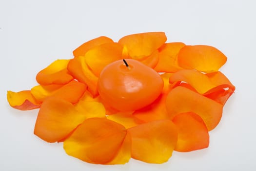 Spilt petals of the orange-rose around the aromatic candle