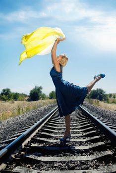 Dancing model with yellow fabric on the railway 