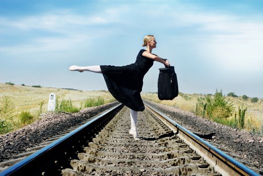 Ballet dancer with luggage on the railroad
