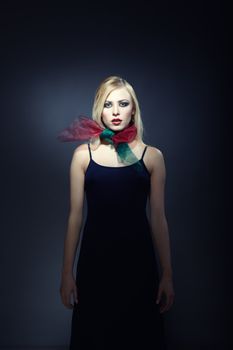 Model in stylish dress and scarf posing on a dark studio background