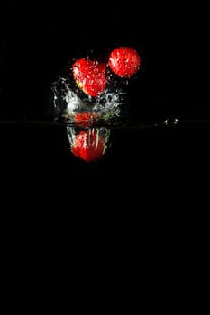 Colored red paprika in water splashes on black background