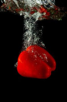 Colored red paprika in water splashes on black background