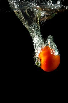 fresh tomato uder water on black background