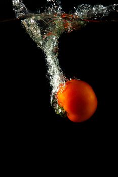 fresh tomato uder water on black background