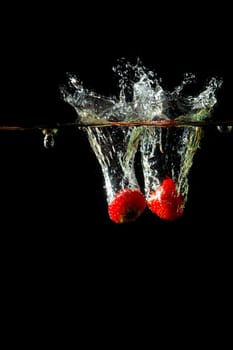 Colored red paprika in water splashes on black background