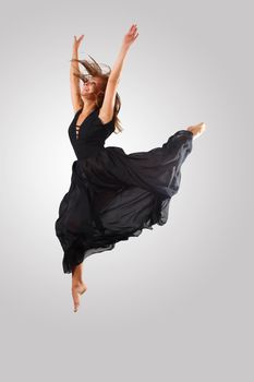 Young female dancer jumping against white background