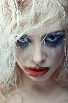 Blond female witch with strange makeup. Studio photo