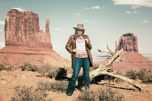 blond cowgirl holding wanted paper at Monument Valley