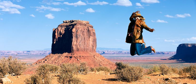 panoramic view of cowgirl jumping in front of Monument Valley, Utah, USA