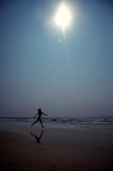 Silhouette of the woman running at the beach