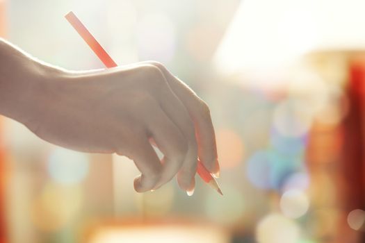 Hand of human holding red pencil. Close-up photo