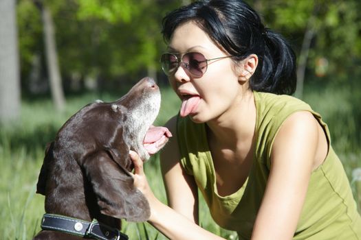 Joyful girl playing and teasing dog outdoors. Horizontal photo with natural colors