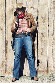 Portrait of a cowgirl blowing on his gun