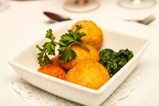 An appetizer of conch fritters with sauce, gsarnish and parsley