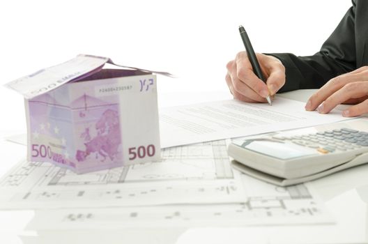 Signing contract of house sale with house made of 500 Euro money and  architectural building plan on a white table.