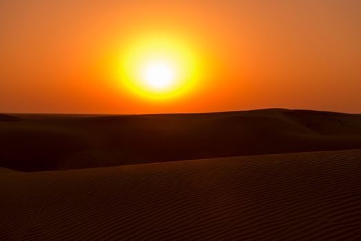 Big yellow sun under sand dunes in desert at sunset. Thar desert or Great Indian desert.