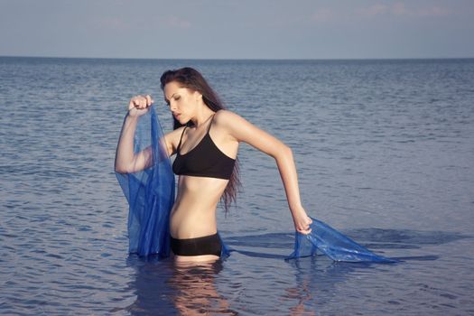 Woman with blue fiber dancing in the sea