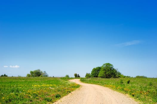 Rural expanse. Dirt road between green hills