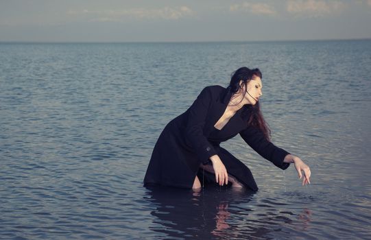 Lady in wet coat dancing in the sea