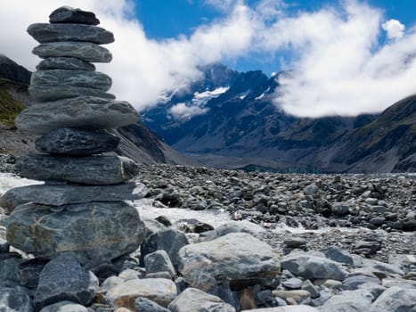 Rock cairn in Hooker Valley on a trail leading to Aoraki  Mount Cook  highest peak of Southern Alps  an icon of New Zealand partially covered in clouds