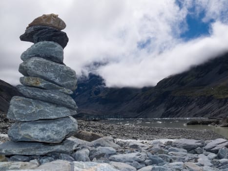 Rock cairn in Hooker Valley on a trail leading to Aoraki  Mount Cook  highest peak of Southern Alps  an icon of New Zealand covered in clouds