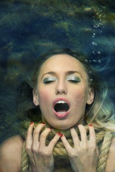 Gapsing woman with rope on her neck going under. Underwater view