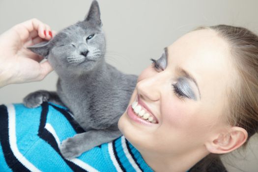 Smiling woman holding and pampering cat indoors