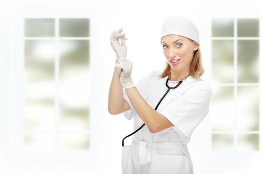 Pretty female doctor putting on the latex gloves in the clinic with big windows