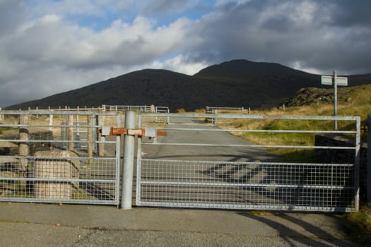 A road with locked metal security gates with mountains in the background.