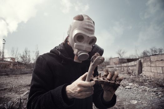 Man in gas mask holding residual bones after doomsday