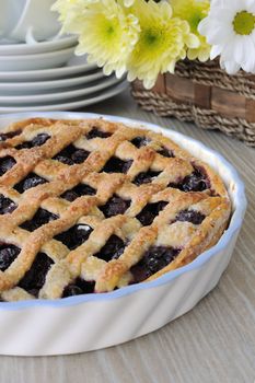 Tart of puff pastry with cherries on the table with flowers and kitchenware