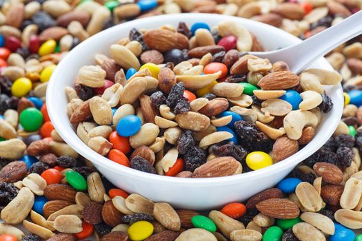 Colorful trail mix in a white bowl with spoon