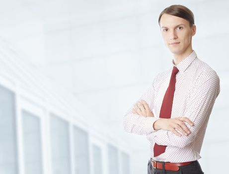 Young businessman with arms crossed at his office