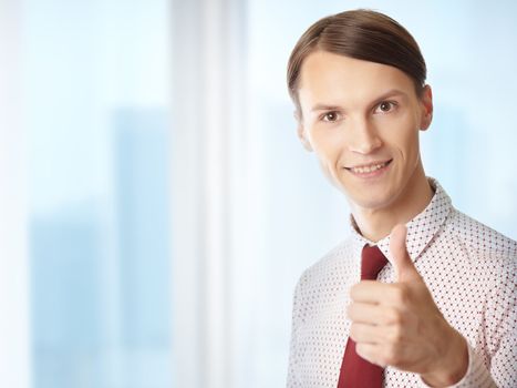 Successful businessman making thumbs up gesture in his office