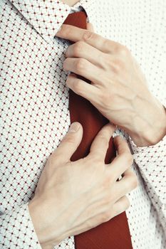 Close-up photo of the businessman knotting his red necktie