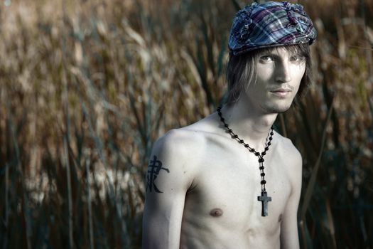 Topless man with cap on the head and black religious cross. Artistic colors added