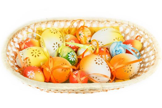 painted easter eggs with ribbon in basket on white background