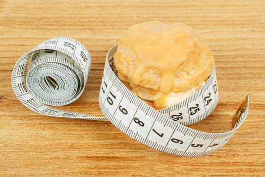concept of slimming, caramel cake with measuring tape on desk